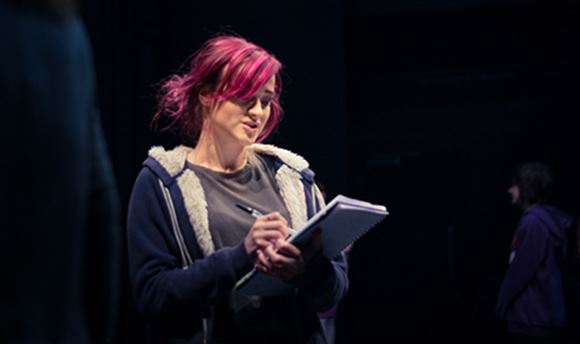 A Ƶ stage management student reading and making notes on a notepad on stage